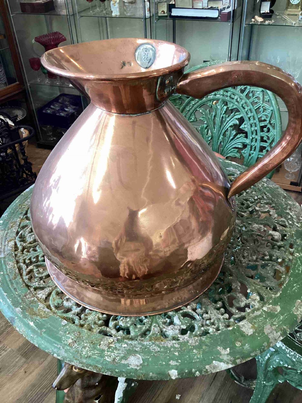 A large Victorian polished copper ale jug with a wide bulbous body, flared neck, stamped verification mark, and robust strap handle.