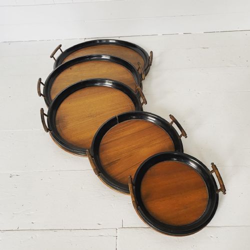 A Graduated Ebonised Set of Five Circular Trays