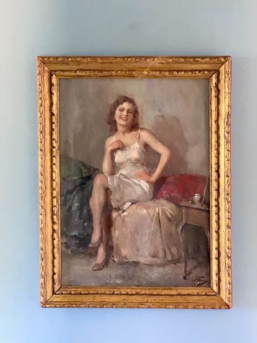 fig 1. An oil painting depicting a seated woman in a light dress contained within an ornate gilt wooden frame.