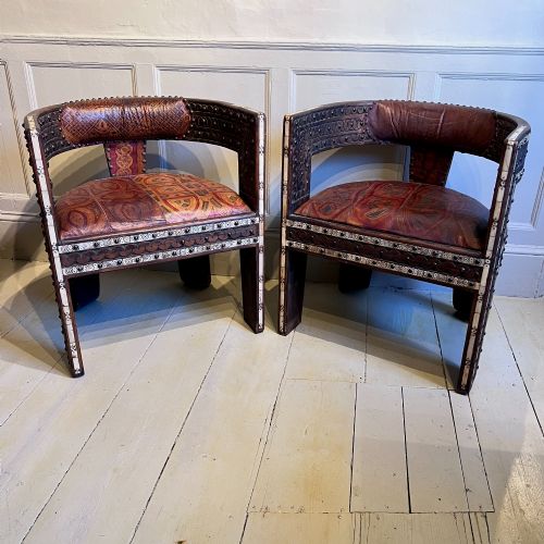fig 1. A pair of low curved hardwood armchairs featuring geometric bone inlay, brass stud detailing, and patterned red leather seats.