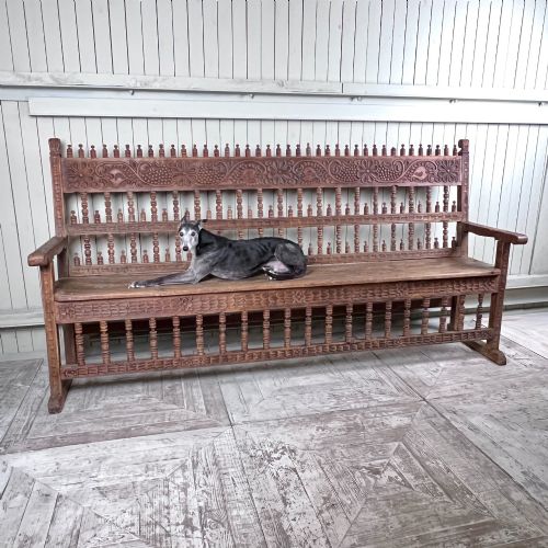 fig 2. A large antique Spanish Colonial carved hardwood bench with floral relief carving and turned spindle details along the back and base.