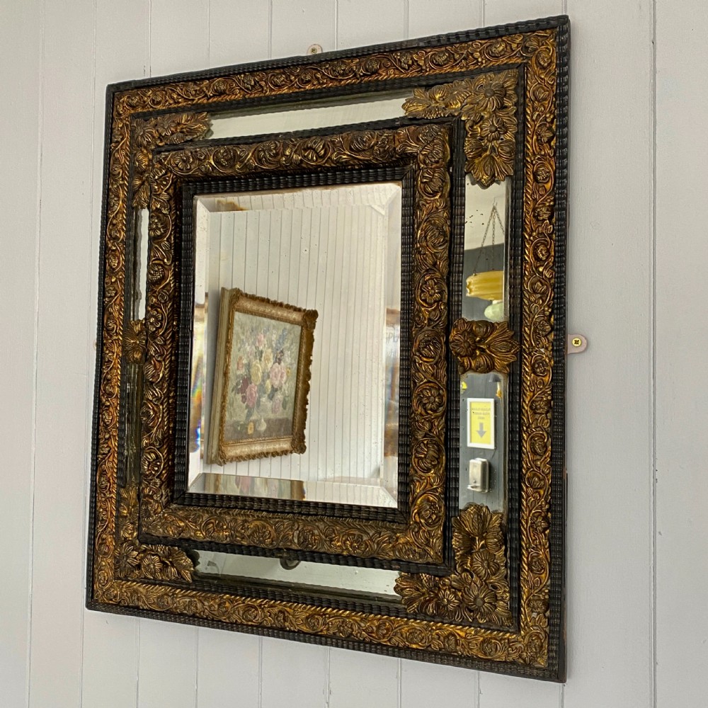 A Repousse Brass and Ebonised Cushion Mirror