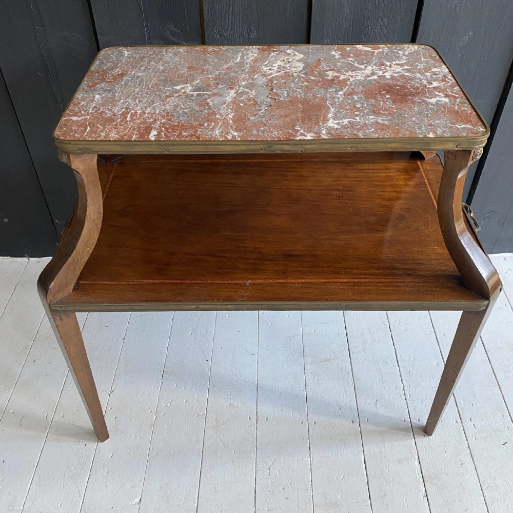 A two-tiered mahogany side table featuring a pink-veined marble top framed in brass, supported by curved legs over a lower wood shelf with brass side handles. View IV