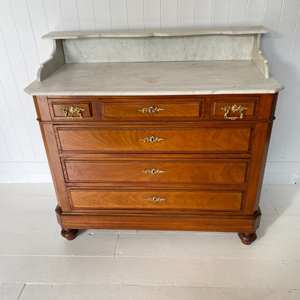 A 19th-century French walnut commode featuring four drawers, decorative brass handles, turned feet, and a white marble top with an upper marble shelf. View III