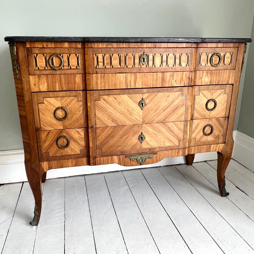 An antique Continental parquetry wooden commode featuring geometric wood inlays, brass ring handles, and a dark grey marble top. View III