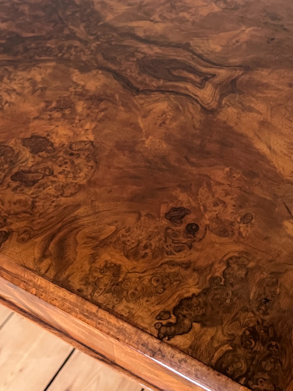 A Victorian burr walnut occasional table featuring a highly figured wood grain top, dual turned pedestals connected by a stretcher, and carved splayed legs on brass castors. View IX