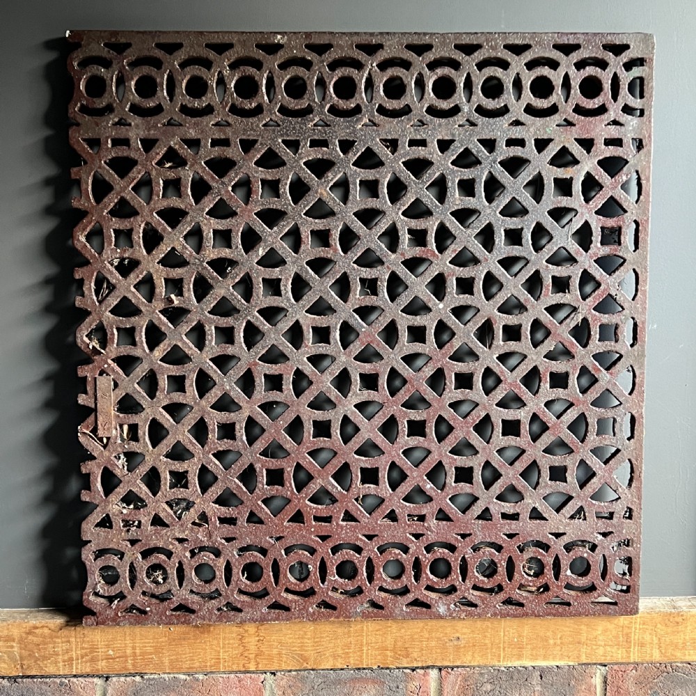 Four heavy rectangular cast iron architectural panels with pierced geometric openwork patterns and a weathered rust brown finish. View II