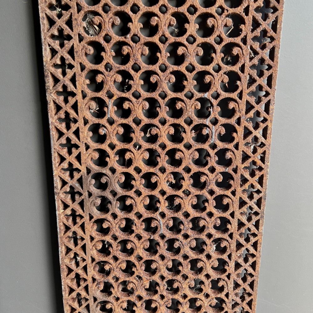 Four heavy rectangular cast iron architectural panels with pierced geometric openwork patterns and a weathered rust brown finish. View III