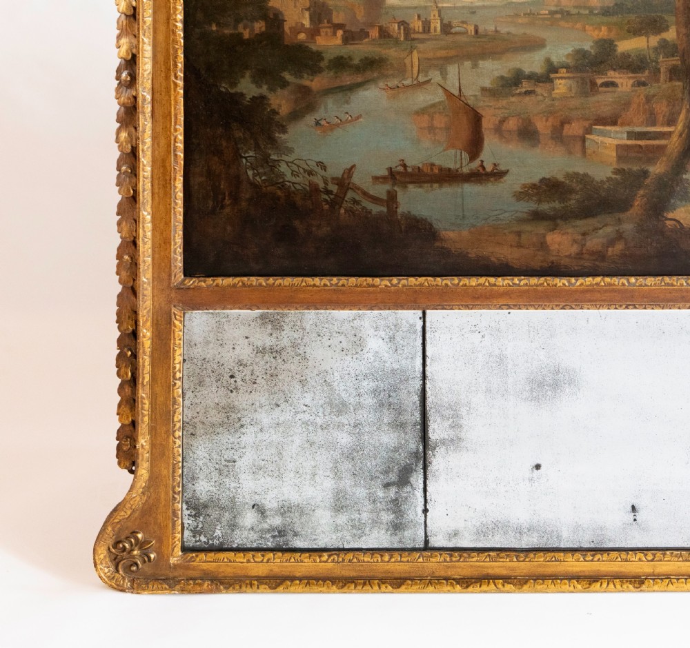 A large Georgian giltwood overmantel trumeau mirror featuring a classical oil painting of a landscape above three antiqued mirror plates. View IV