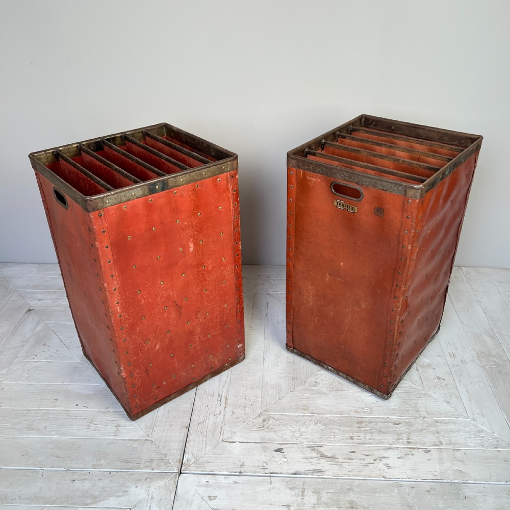 A pair of tall, terracotta-red industrial storage bins with metal-trimmed rims, riveted edges, cut-out side handles, and internal slots. View II