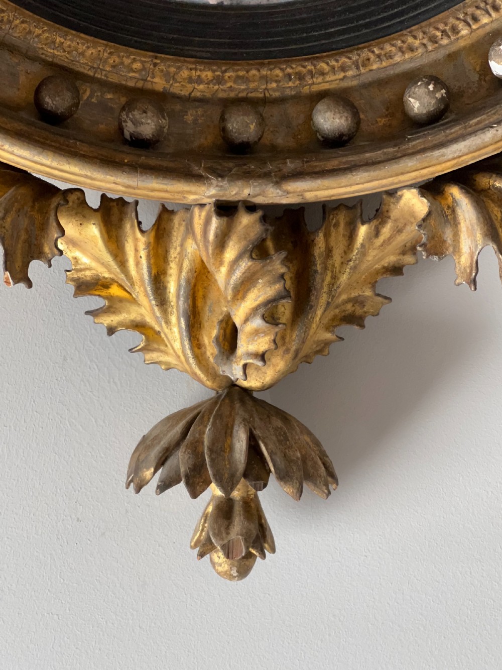 A circular Regency giltwood convex wall mirror topped with a carved eagle cresting and decorated with spherules along the frame. View IV