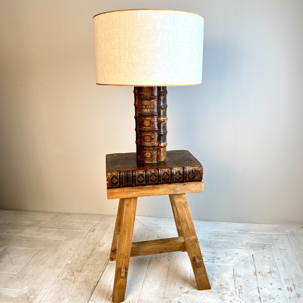 A table lamp featuring a column and base crafted from antique leather-bound book spines topped with a neutral drum shade. View III