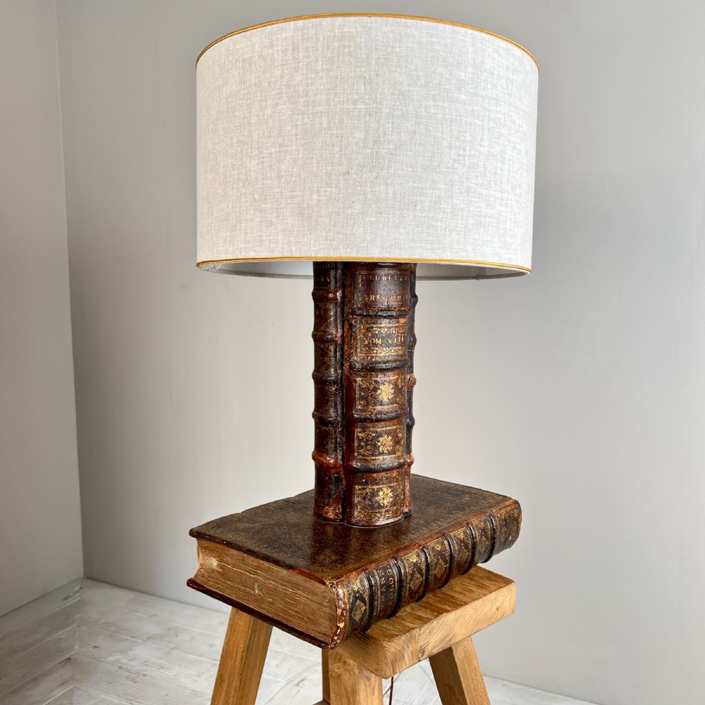 A table lamp featuring a column and base crafted from antique leather-bound book spines topped with a neutral drum shade. View IX