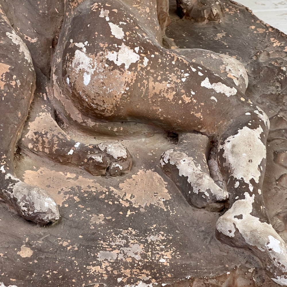 An antique brown terracotta and white painted plaster sculpture depicting a female figure embracing a lion on a naturalistic base. View II