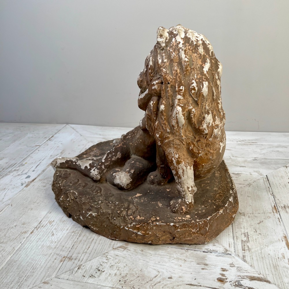 An antique brown terracotta and white painted plaster sculpture depicting a female figure embracing a lion on a naturalistic base. View III