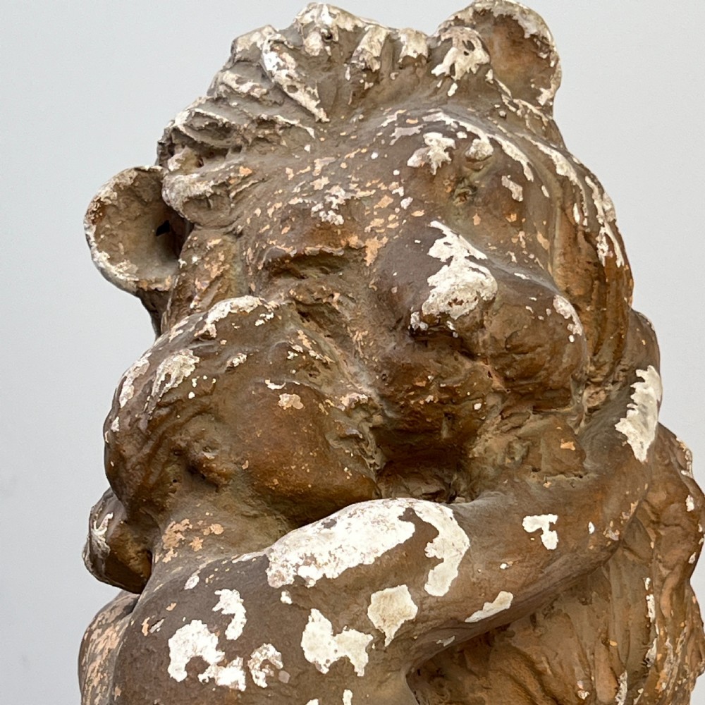An antique brown terracotta and white painted plaster sculpture depicting a female figure embracing a lion on a naturalistic base. View VII