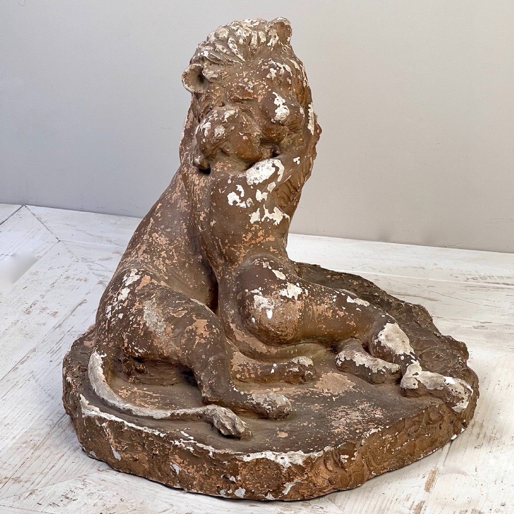 An antique brown terracotta and white painted plaster sculpture depicting a female figure embracing a lion on a naturalistic base. View VIII
