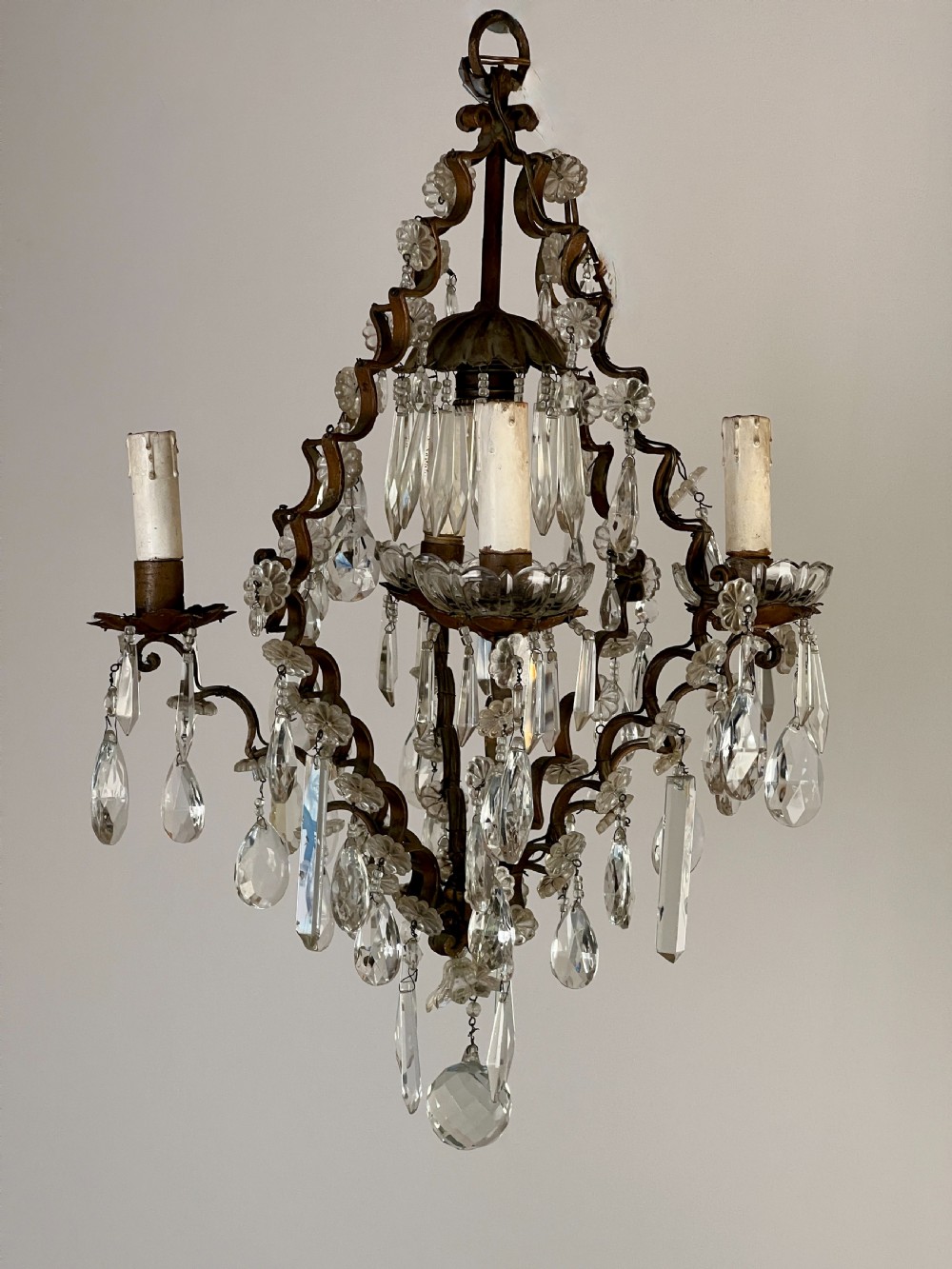An antique French cage chandelier featuring an openwork metal frame decorated with clear glass rosettes, cut crystal teardrop prisms, and four candle-style light sockets. View II