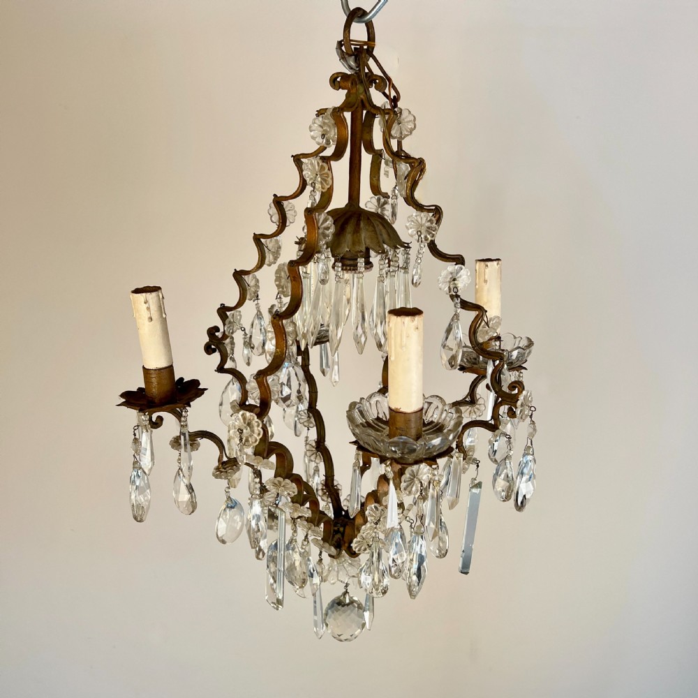 An antique French cage chandelier featuring an openwork metal frame decorated with clear glass rosettes, cut crystal teardrop prisms, and four candle-style light sockets. View IV