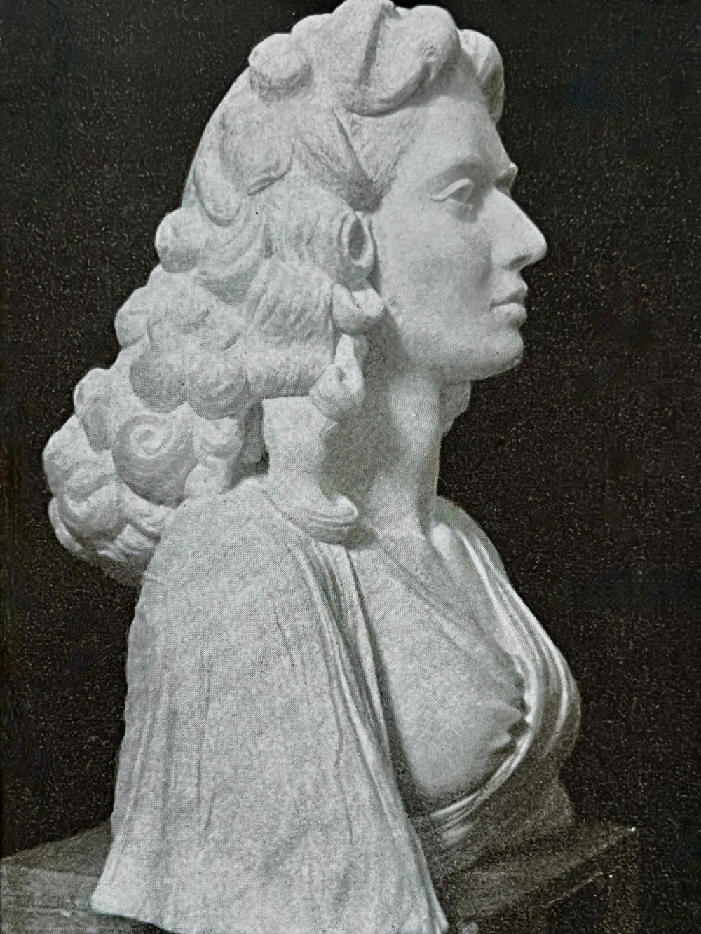 A carved off-white marble bust depicting a lady with styled hair and a serene expression, mounted on a matching square marble plinth. View X