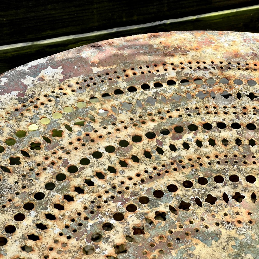 A circular French antique wrought iron garden table featuring a perforated metal top, curved legs with a central stretcher ring, and a heavily patinated weathered paint finish. View III