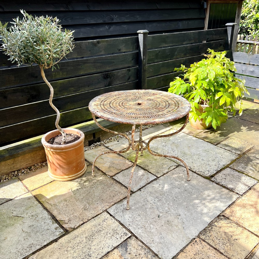 A circular French antique wrought iron garden table featuring a perforated metal top, curved legs with a central stretcher ring, and a heavily patinated weathered paint finish. View V