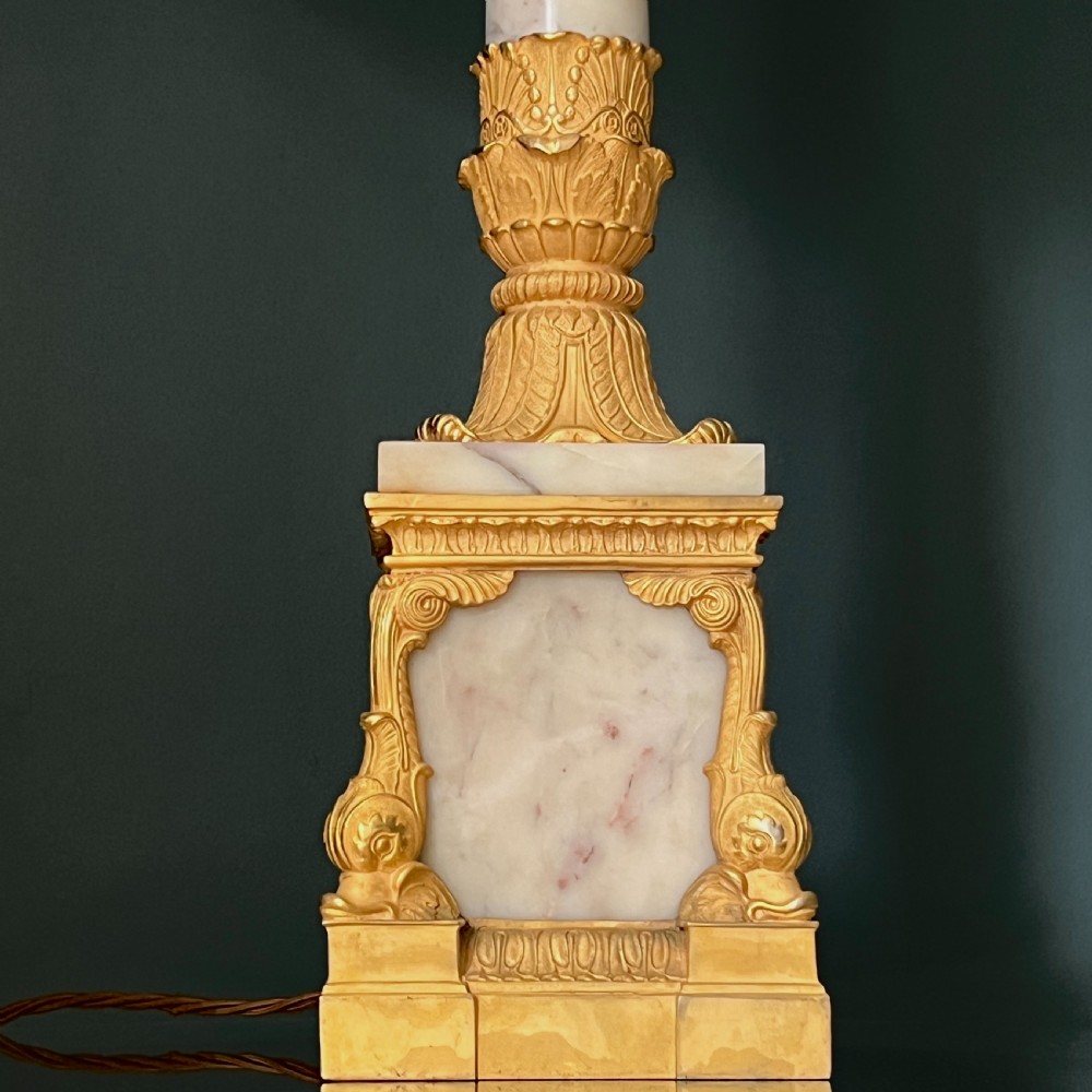 An Empire style table lamp featuring a white marble column base with gold ormolu leaf mounts and a large cream drum shade. View III