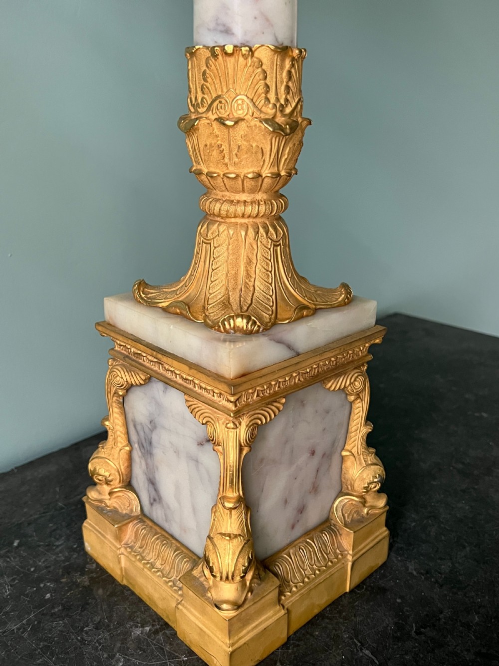 An Empire style table lamp featuring a white marble column base with gold ormolu leaf mounts and a large cream drum shade. View VII