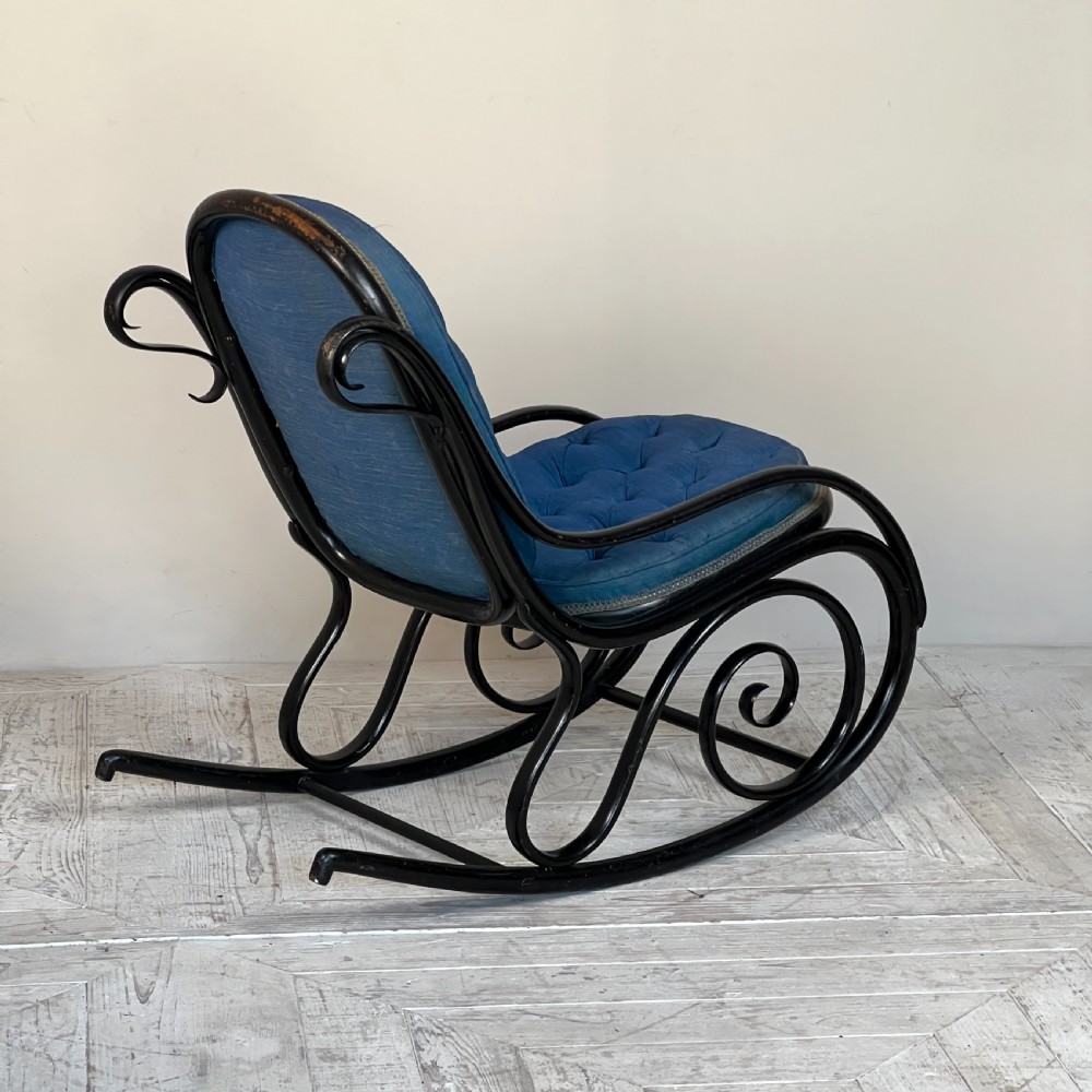 A Victorian ebonised bentwood rocking chair featuring elaborate curved scrollwork frame and deep blue button-tufted upholstery. View IV