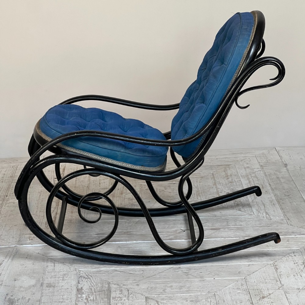 A Victorian ebonised bentwood rocking chair featuring elaborate curved scrollwork frame and deep blue button-tufted upholstery. View V