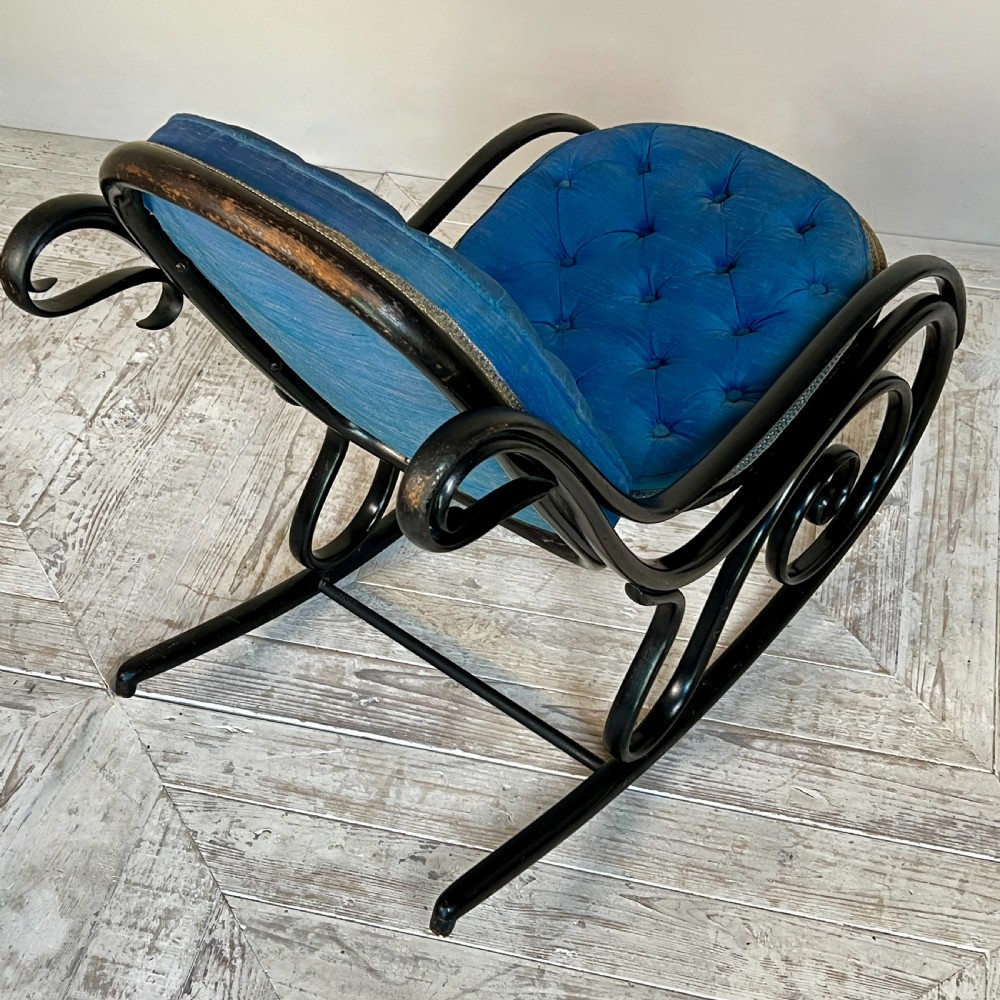 A Victorian ebonised bentwood rocking chair featuring elaborate curved scrollwork frame and deep blue button-tufted upholstery. View VI