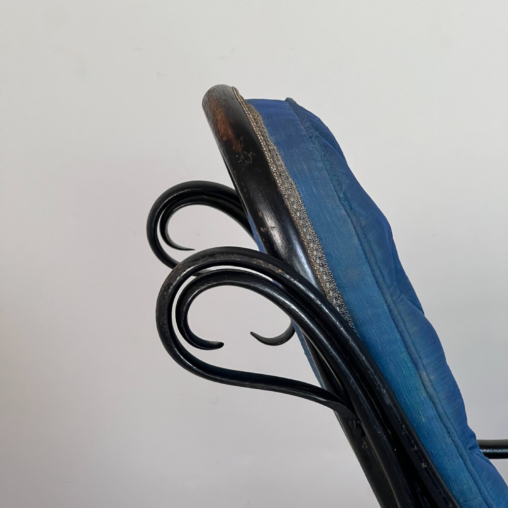 A Victorian ebonised bentwood rocking chair featuring elaborate curved scrollwork frame and deep blue button-tufted upholstery. View VII