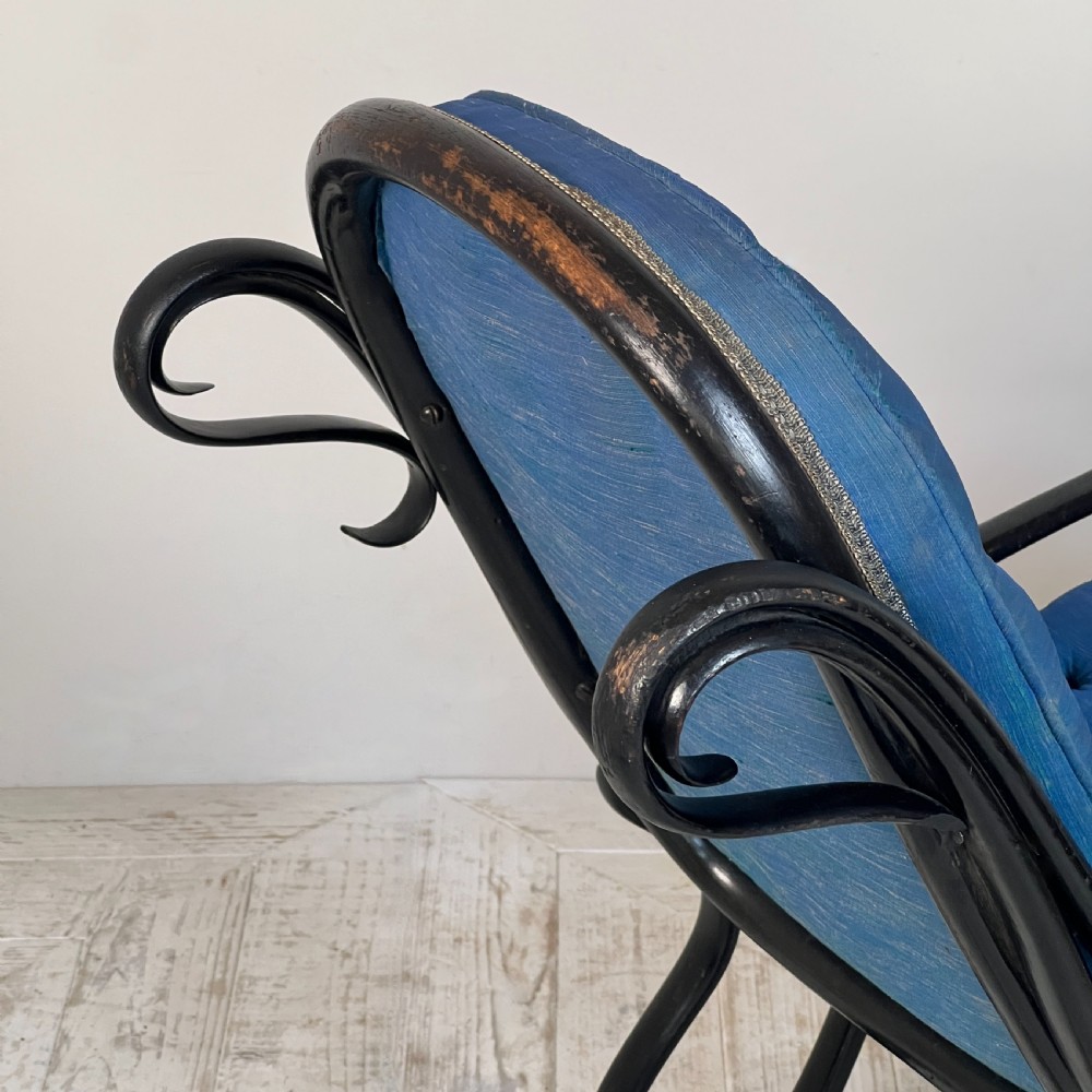 A Victorian ebonised bentwood rocking chair featuring elaborate curved scrollwork frame and deep blue button-tufted upholstery. View IX