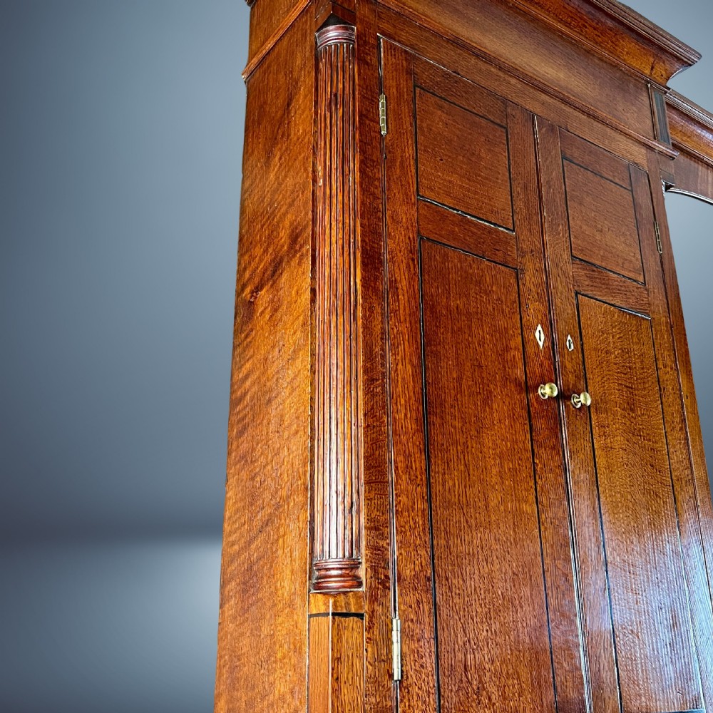 A large Georgian oak breakfront housekeepers cupboard featuring twin side cabinets with drawers, central open shelves, and brass swan-neck handles. View VI