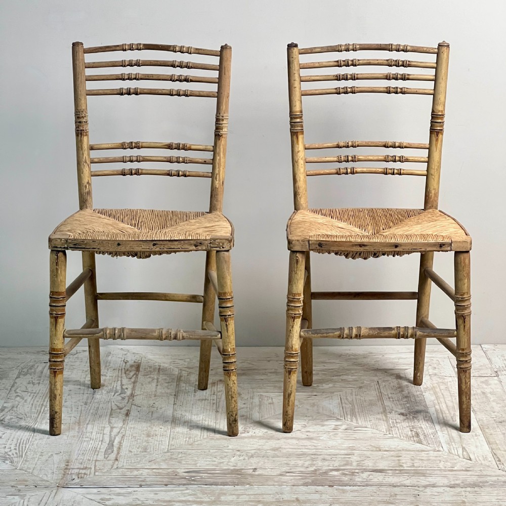 A pair of antique Regency side chairs featuring painted faux bamboo turned frames and woven rush seats. View II