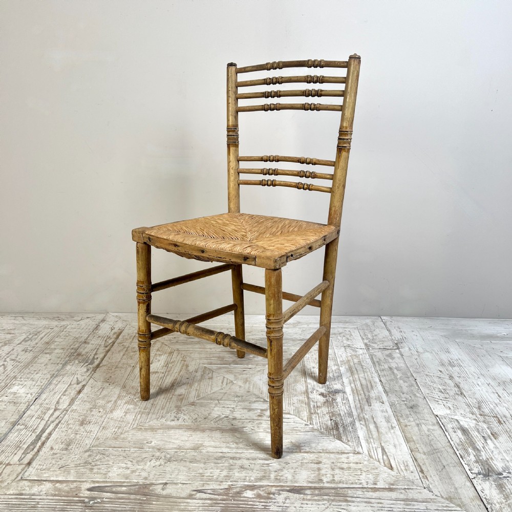 A pair of antique Regency side chairs featuring painted faux bamboo turned frames and woven rush seats. View IV