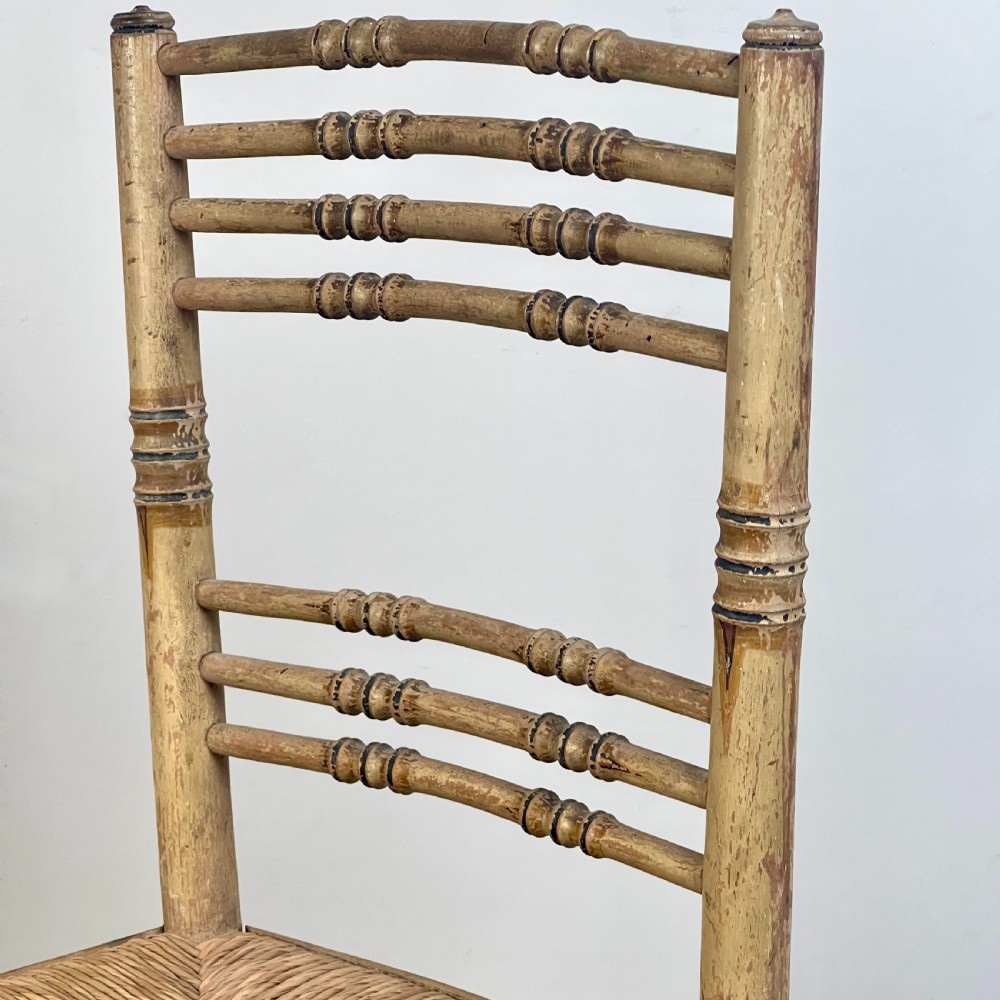 A pair of antique Regency side chairs featuring painted faux bamboo turned frames and woven rush seats. View V