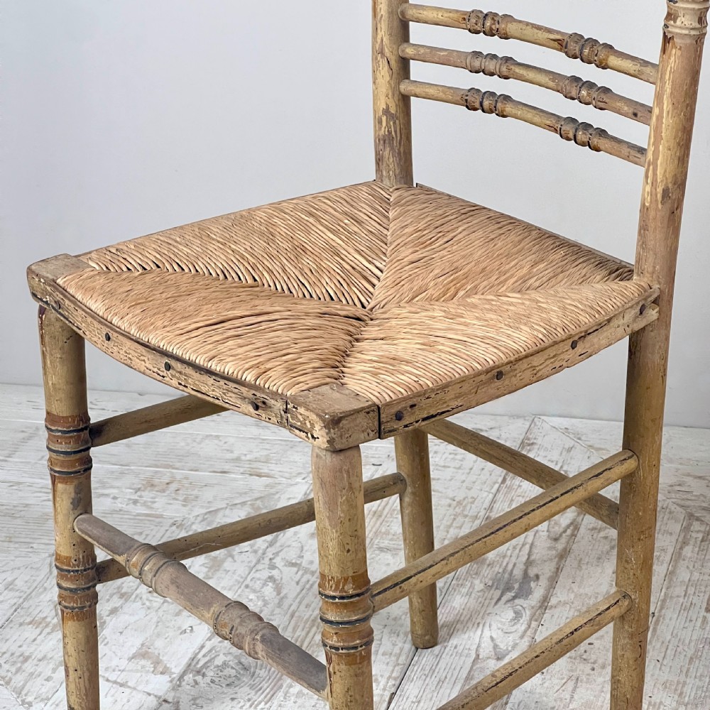 A pair of antique Regency side chairs featuring painted faux bamboo turned frames and woven rush seats. View VI