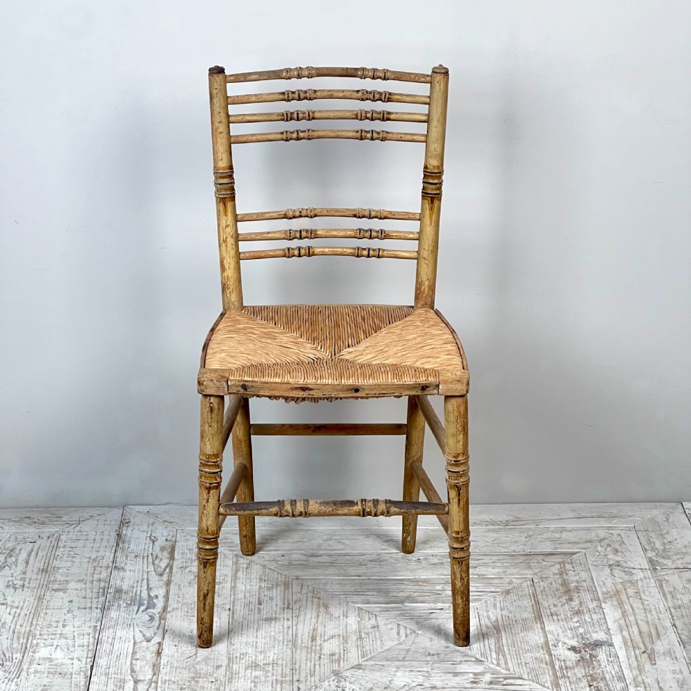 A pair of antique Regency side chairs featuring painted faux bamboo turned frames and woven rush seats. View IX