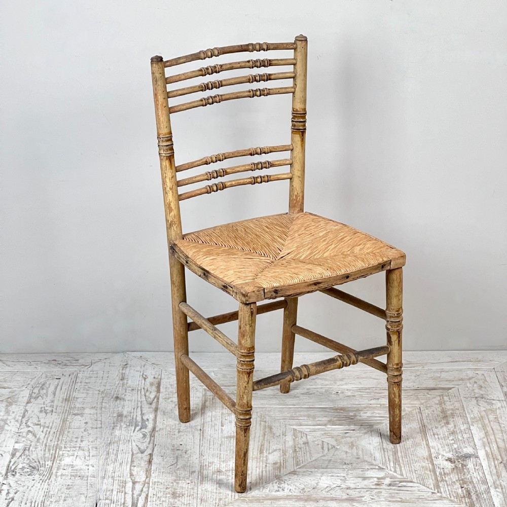 A pair of antique Regency side chairs featuring painted faux bamboo turned frames and woven rush seats. View X