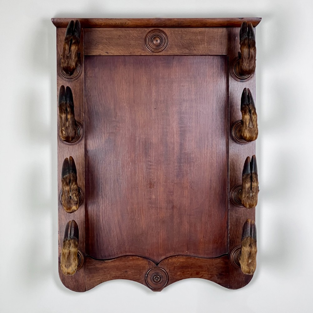 A rectangular dark oak wall rack featuring eight mounted taxidermy deer hooves serving as coat hooks arranged vertically along both sides. View II
