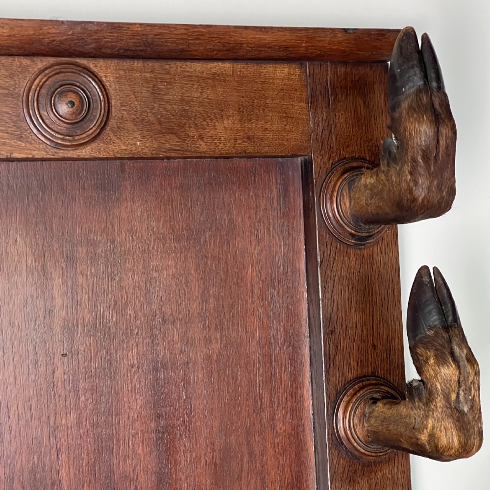 A rectangular dark oak wall rack featuring eight mounted taxidermy deer hooves serving as coat hooks arranged vertically along both sides. View III