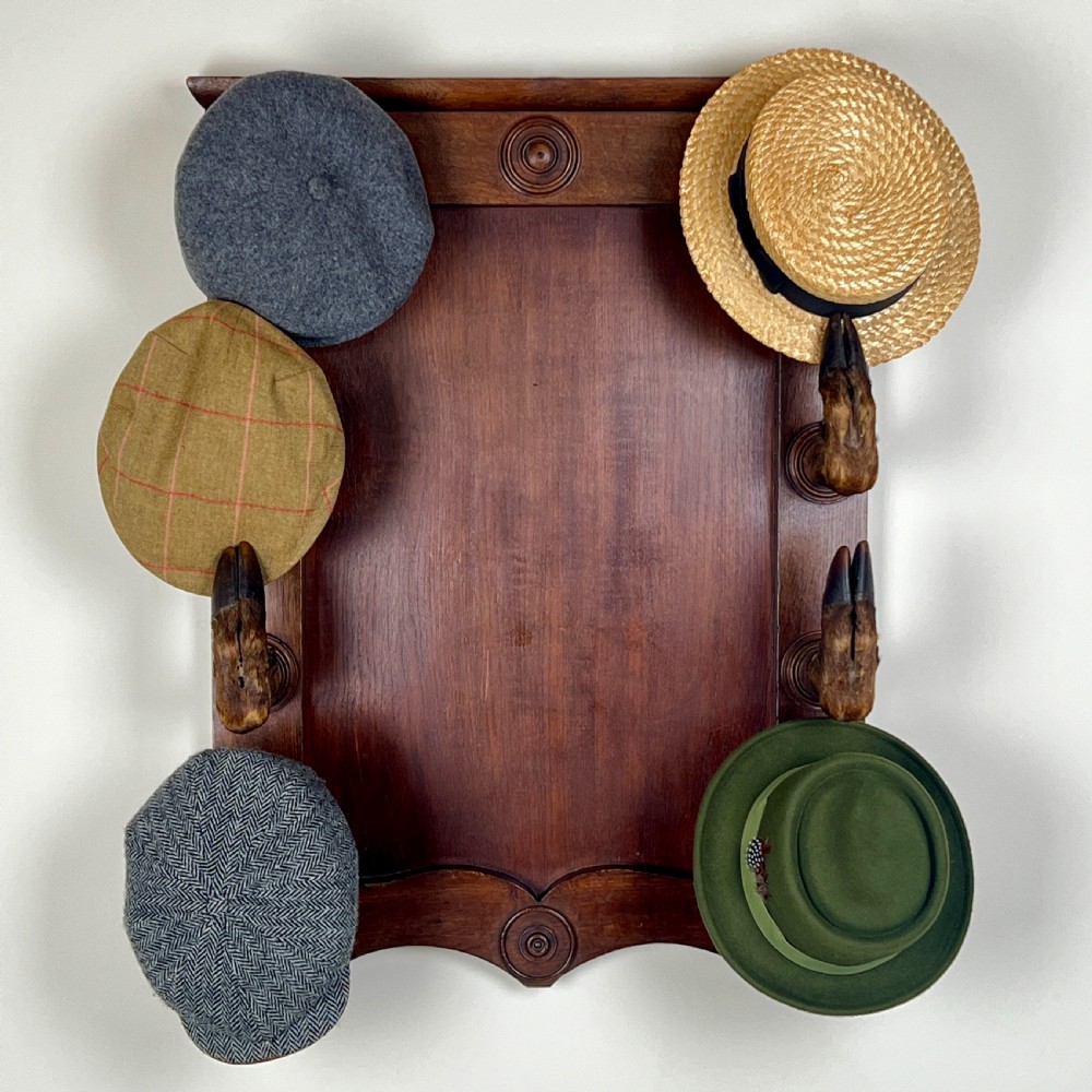 A rectangular dark oak wall rack featuring eight mounted taxidermy deer hooves serving as coat hooks arranged vertically along both sides. View VIII