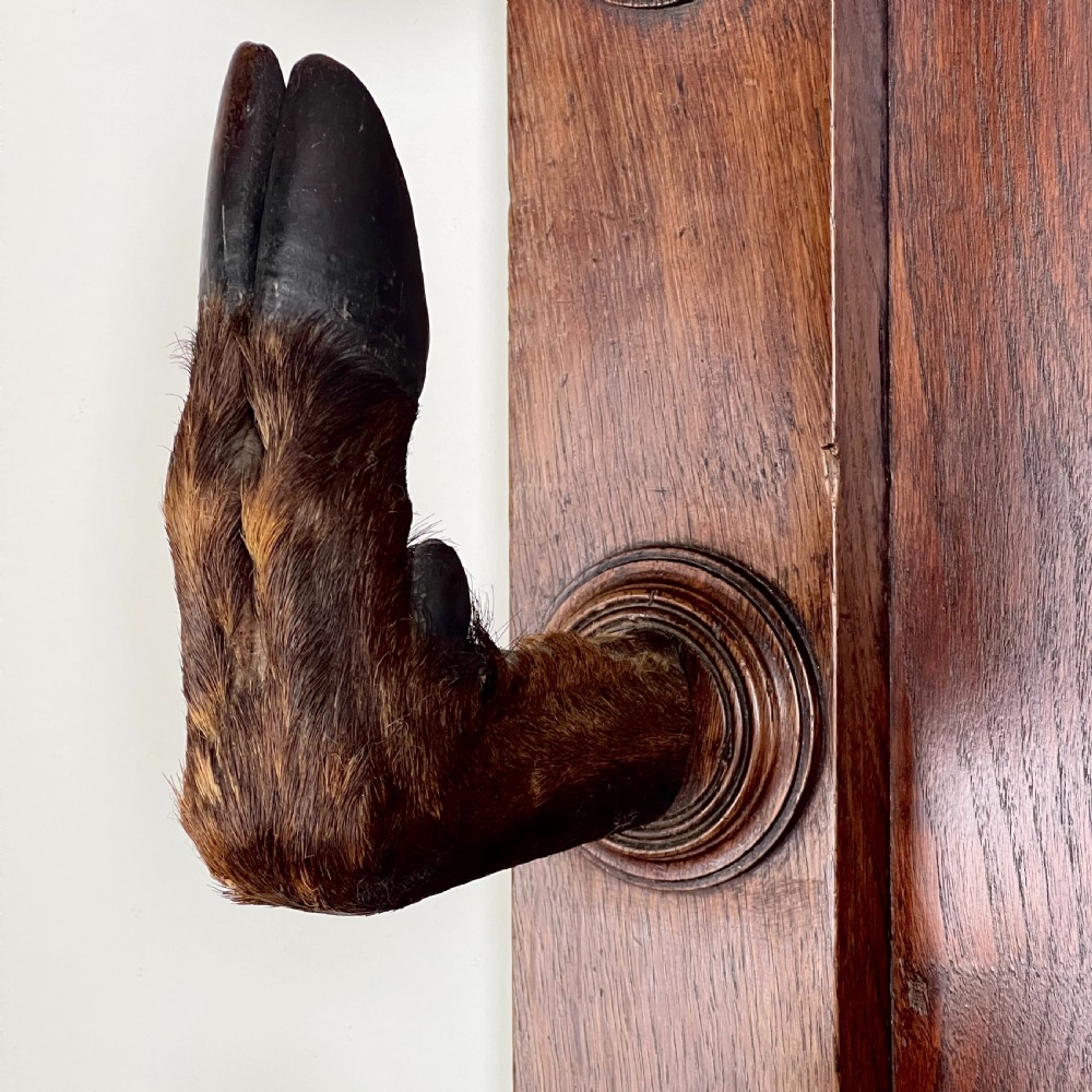 A rectangular dark oak wall rack featuring eight mounted taxidermy deer hooves serving as coat hooks arranged vertically along both sides. View XIII