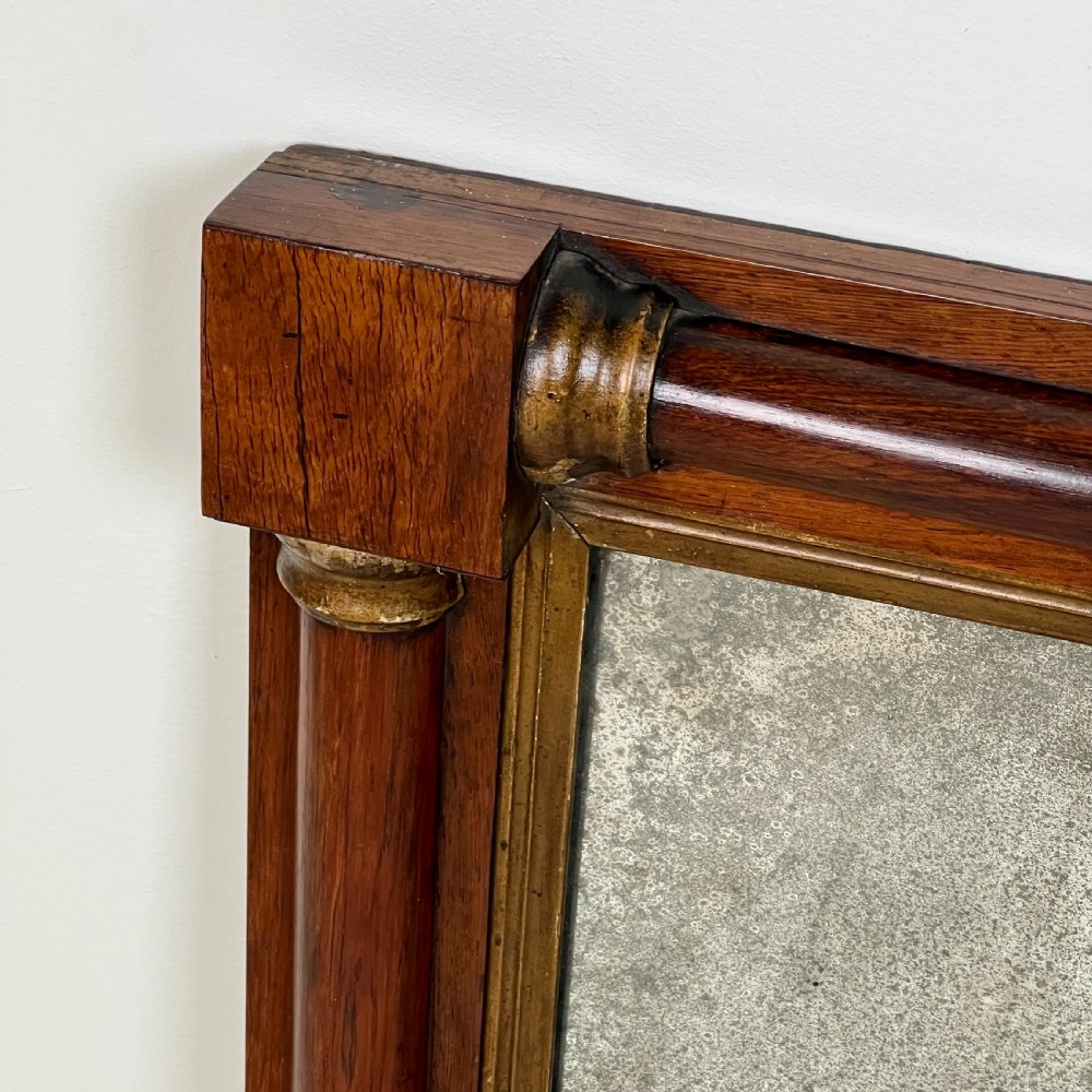 An early 19th-century horizontal mahogany overmantel mirror featuring turned side pilasters, gilt accents, and foxed glass. View III