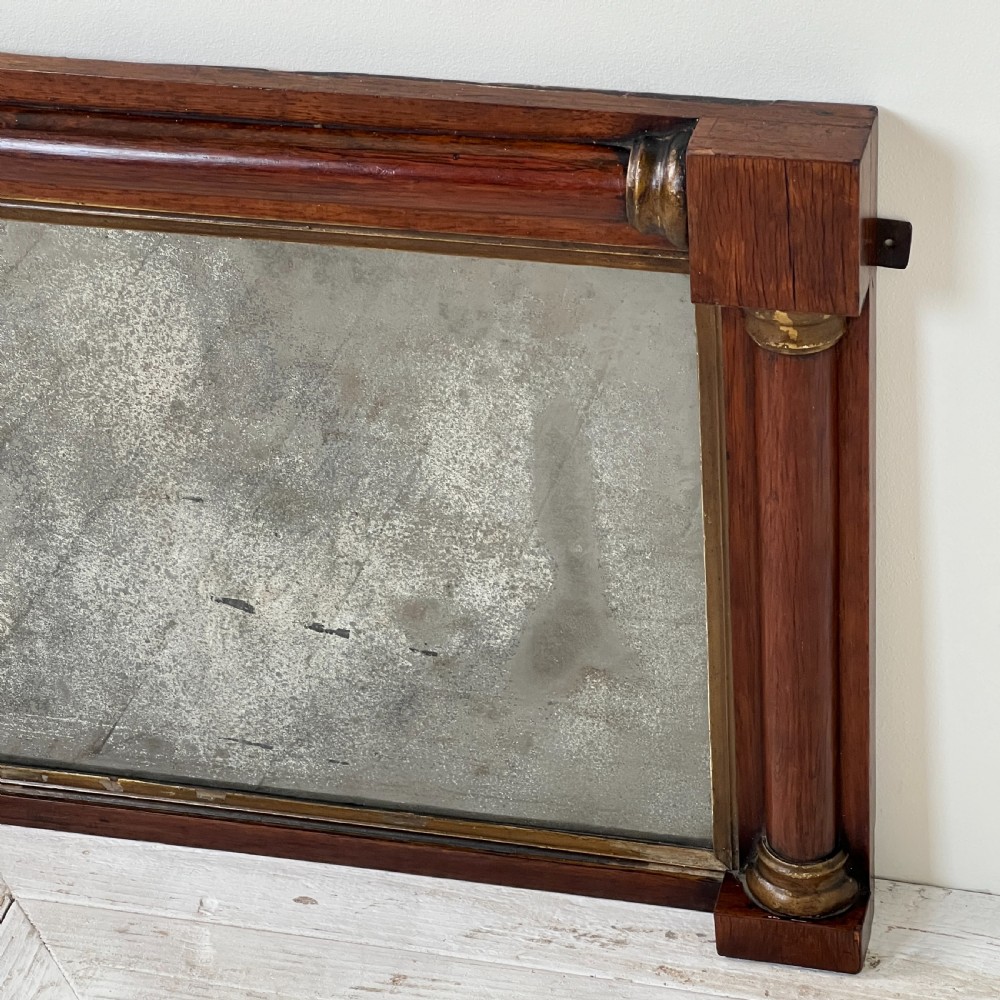 An early 19th-century horizontal mahogany overmantel mirror featuring turned side pilasters, gilt accents, and foxed glass. View VI