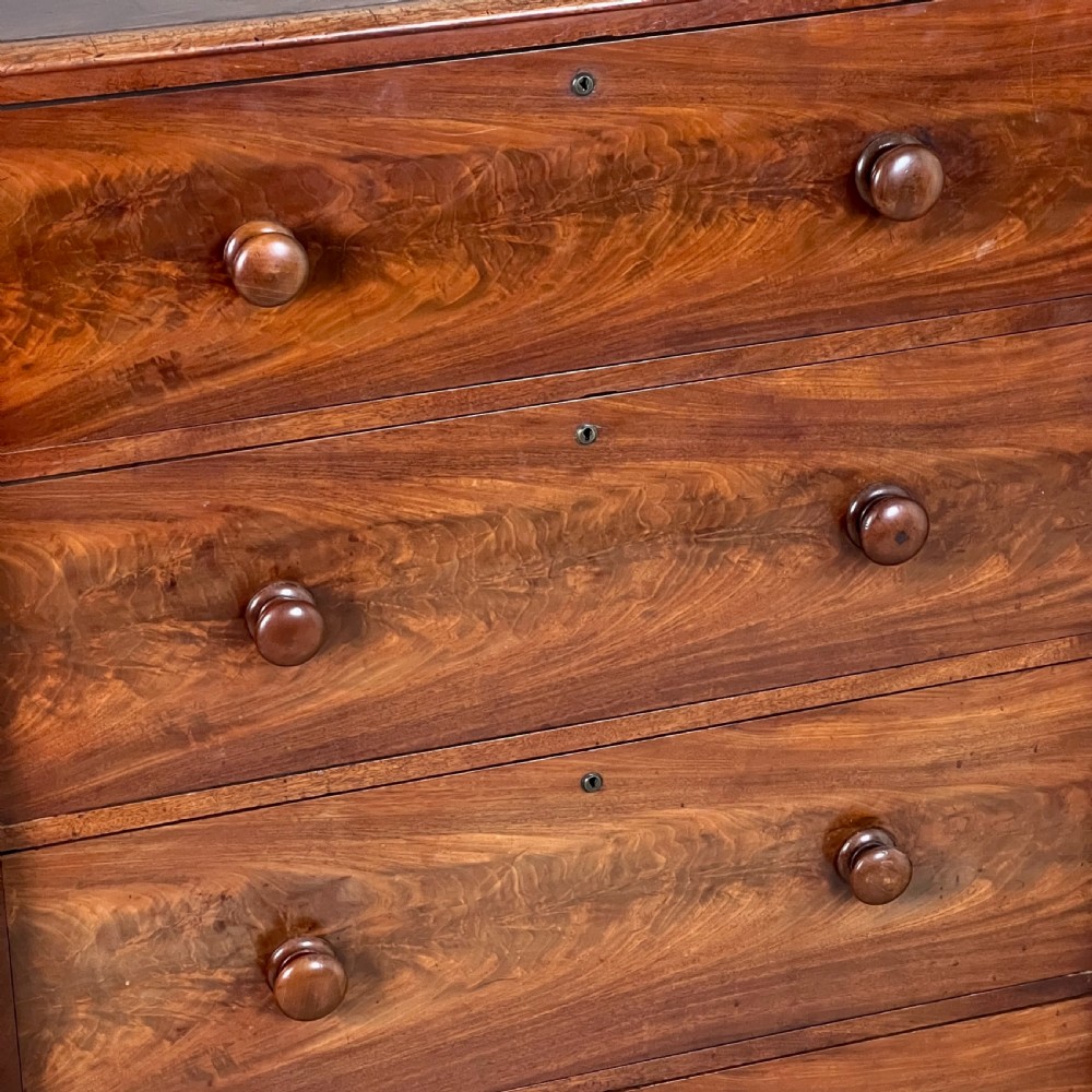 A Victorian flame mahogany breakfront wardrobe featuring a central four-drawer chest flanked by two tall arched cupboards on a plinth base. View V