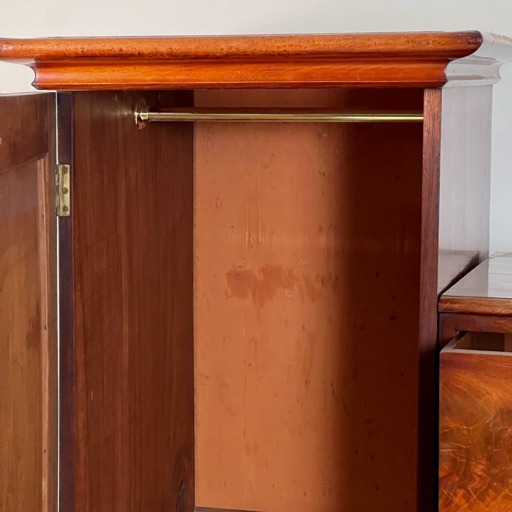 A Victorian flame mahogany breakfront wardrobe featuring a central four-drawer chest flanked by two tall arched cupboards on a plinth base. View VI