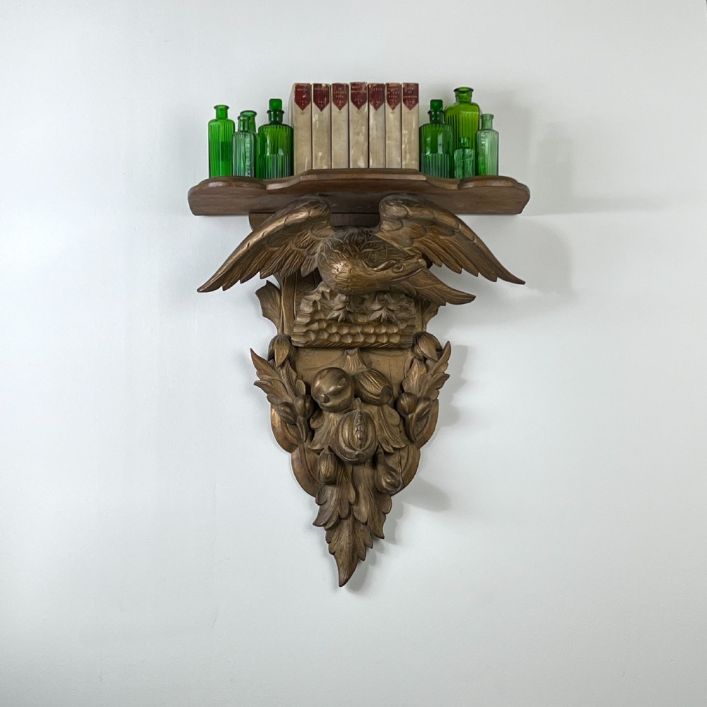 A 19th-century carved giltwood wall bracket featuring a spread-winged eagle above carved fruit and acanthus leaf details. View II