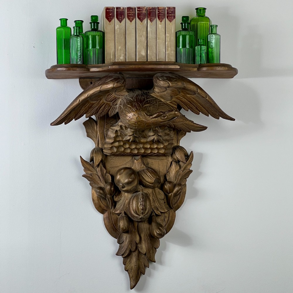 A 19th-century carved giltwood wall bracket featuring a spread-winged eagle above carved fruit and acanthus leaf details. View V